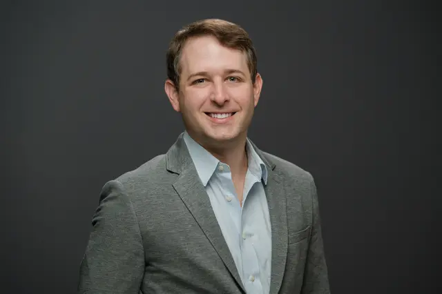Evan Harris, smiling, in a grey blazer and light blue shirt